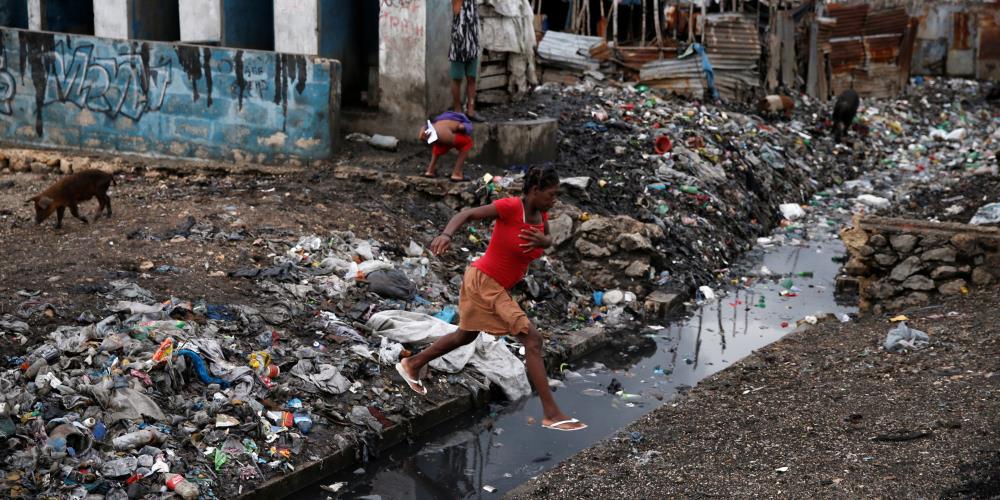 A woman crosses over a water canal after Hurricane Matthew passes Cite-Soleil in Port-au-Prince, Haiti, October 5, 2016. REUTERS/Carlos Garcia Rawlins
