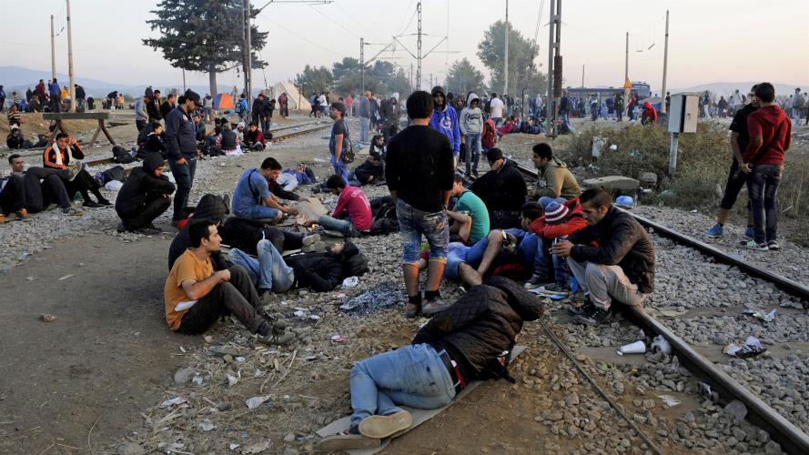 Refugees and migrants rest on railway tracks as they wait to cross the borders of Greece with Macedonia, near the village of Idomeni