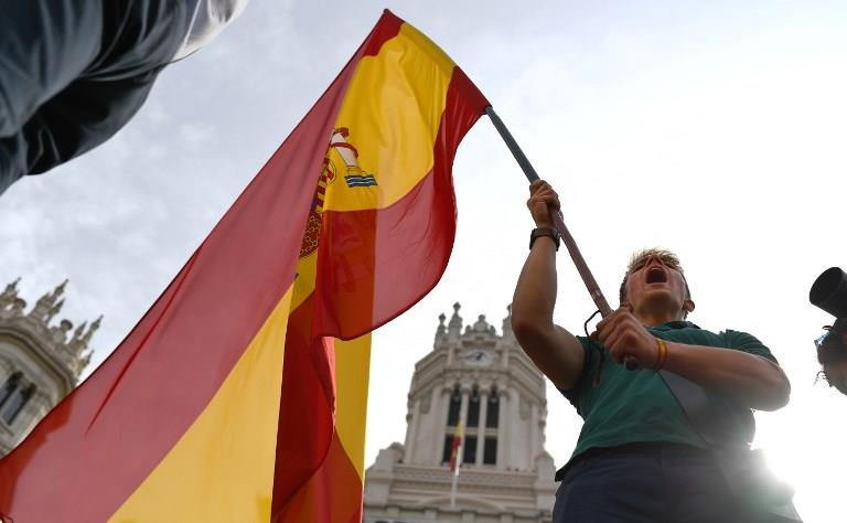 A young man holds a Spanish flag during a demonstration against independence of Catalonia called by DENAES foundation for the Spanish Nation Defence on September 30, 2017 in Madrid. 
Catalan separatists showed determination today to press ahead with an independence referendum banned by Madrid, occupying dozens of schools designated as polling stations to stop police from closing them down. / AFP PHOTO / GABRIEL BOUYS
