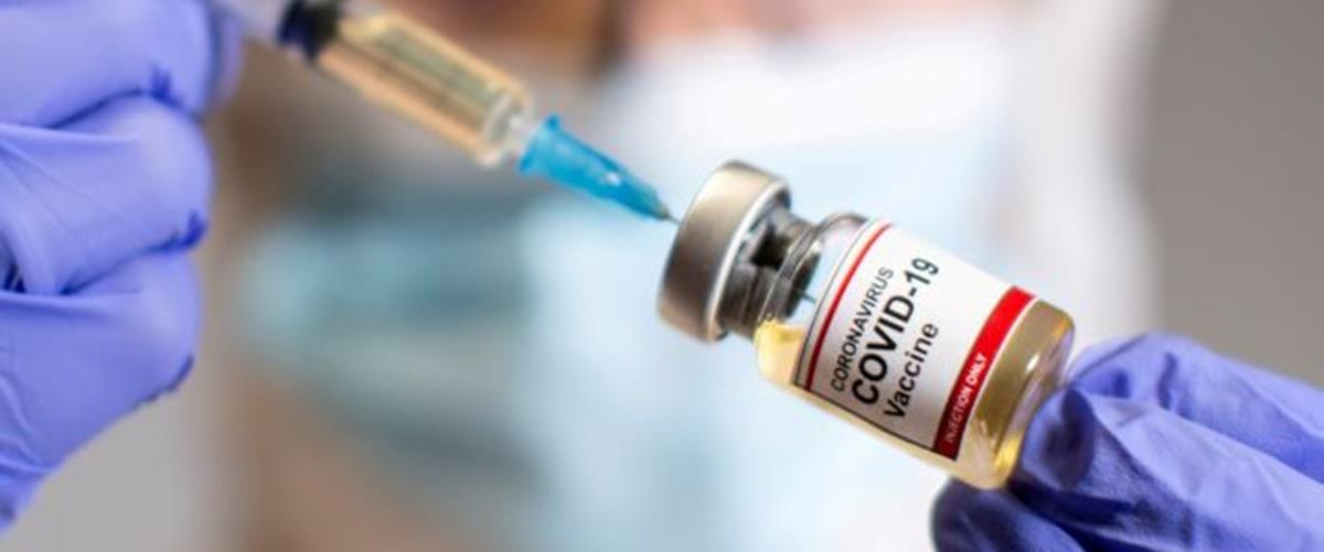 FILE PHOTO: A woman holds a medical syringe and a small bottle labeled "Coronavirus COVID-19 Vaccine