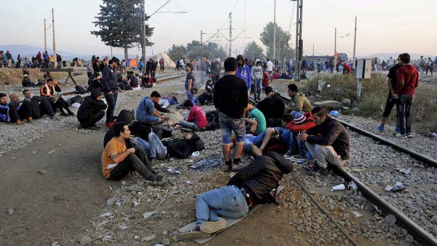 Refugees and migrants rest on railway tracks as they wait to cross the borders of Greece with Macedonia, near the village of Idomeni