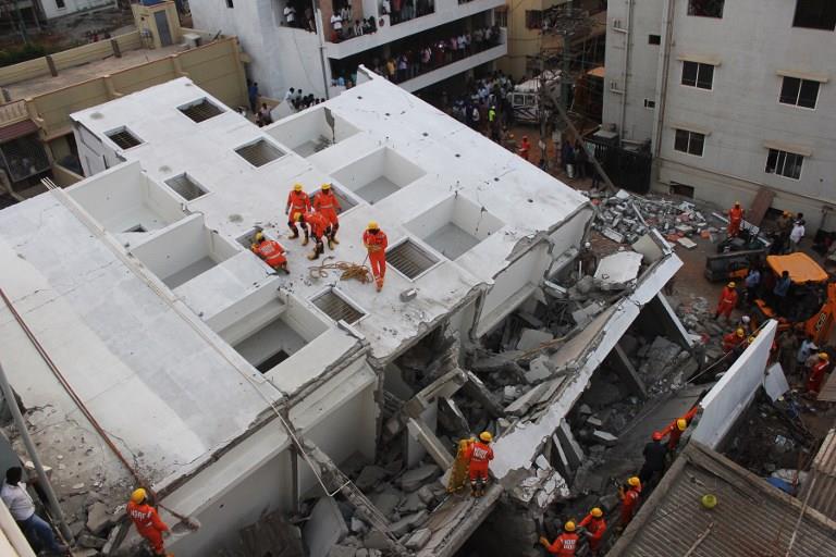 Rescue workers of the fire department and the National Disaster and Relief Force (NDRF) work at the site where a five-storey under construction building collapsed in Bangalore on February 15, 2018. 
Rescue workers recovered three bodies from the site and several others are feared trapped under the rubble, police said. / AFP PHOTO / MANJUNATH KIRAN